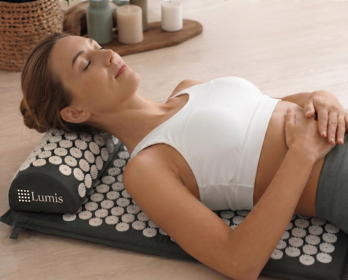 Woman relaxing on Lumis acupressure mat and neck pillow